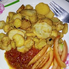 A picture of Chips with stew garnish with tomatoes.
