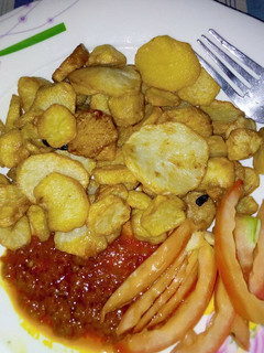A picture of Chips with stew garnish with tomatoes.