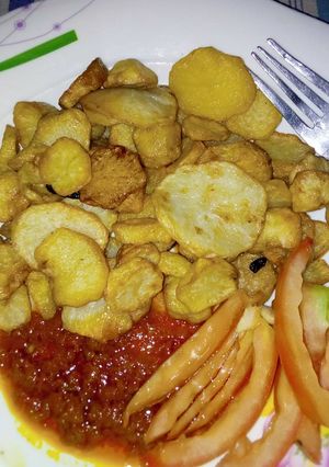 A picture of Chips with stew garnish with tomatoes.