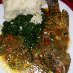 A picture of Stewed fish with greens and ugali.