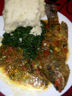 A picture of Stewed fish with greens and ugali.