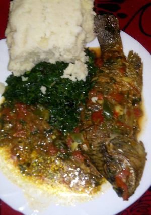 A picture of Stewed fish with greens and ugali.