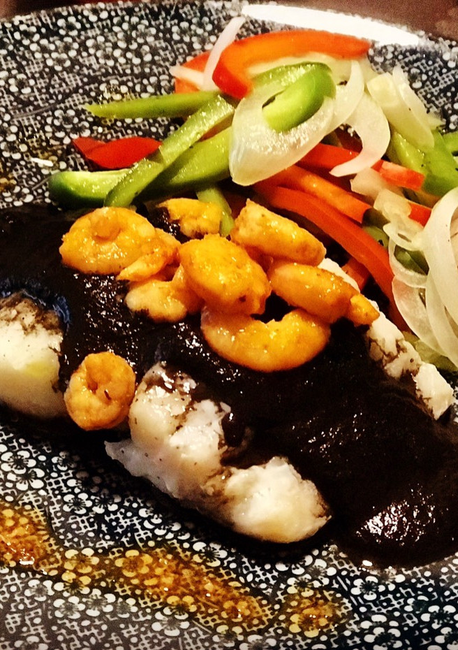 Una foto de Bacalao en papillote con tinta de calamar, gambas picantes y un toque de humo