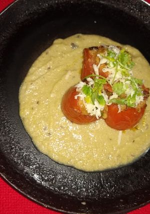 A picture of Stuffed tomato with white gravy.