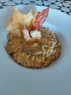 Una foto de Risotto de setas y gambas con crujiente de ibérico y parmesano