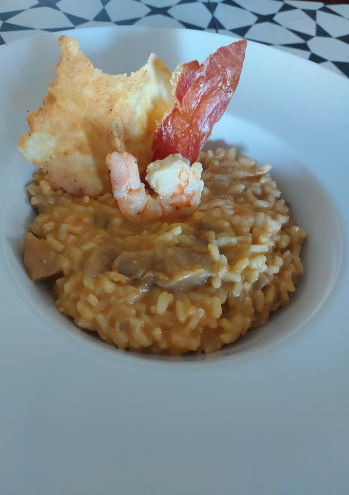 Una foto de Risotto de setas y gambas con crujiente de ibérico y parmesano