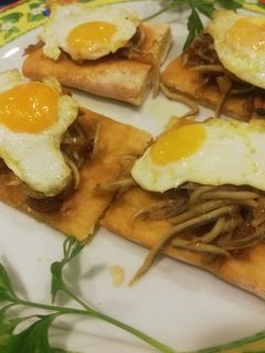 Una foto de Coca de gulas al ajillo y huevo de codorniz y de champiñón con gambas ajillo