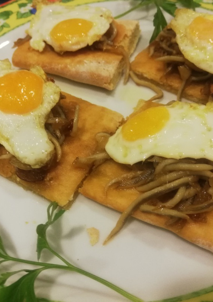 Una foto de Coca de gulas al ajillo y huevo de codorniz y de champiñón con gambas ajillo