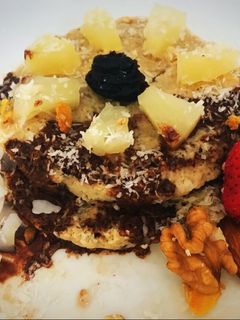 Una foto de Pancakes de banana y avena con ananá, salsa de chocolate, coco y más! Súper saludable y fit