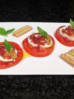 Una foto de Rodajas de mozzarella sobre tomates con jamón curado picadito