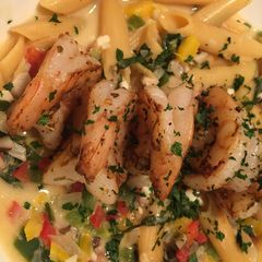 A picture of Cajun grilled shrimp with loaded veggie Alfredo noodles.