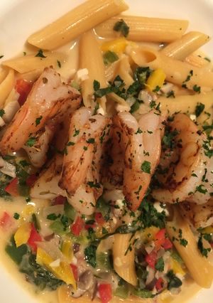 A picture of Cajun grilled shrimp with loaded veggie Alfredo noodles.