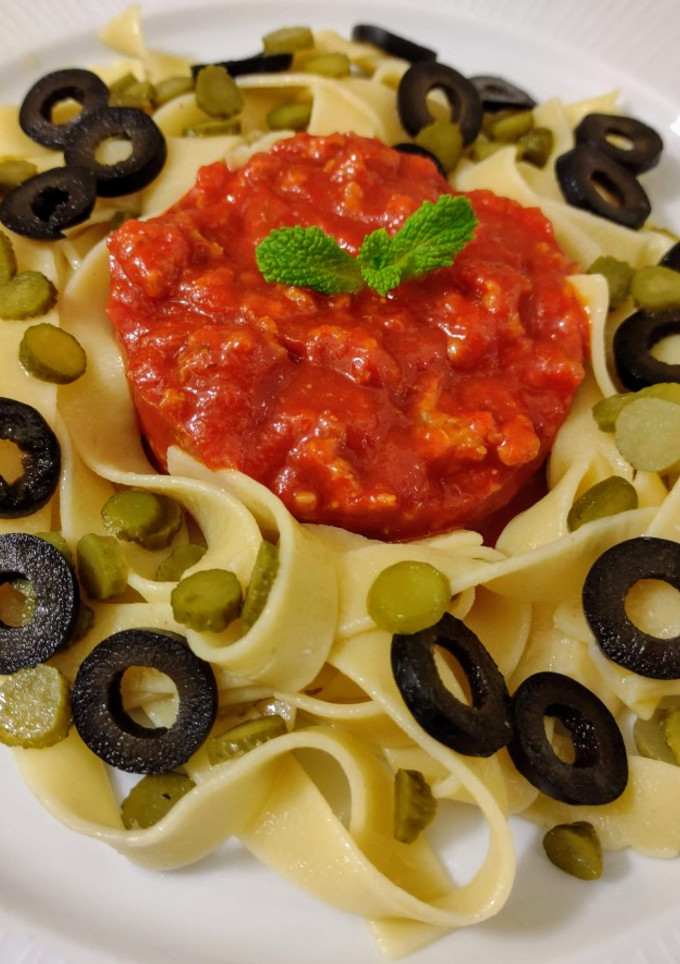 Una foto de Tagliatelles salteados con encurtidos y pesto rosso con nueces