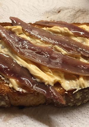 Una foto de Tostada de tomate, queso salmón, anchoas