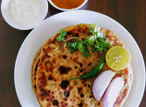 A picture of Dhaba style aloo paratha with mango garlic chutney.