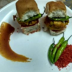 A picture of Authentic vada pav with traditional spicy chutney & fried chilli.
