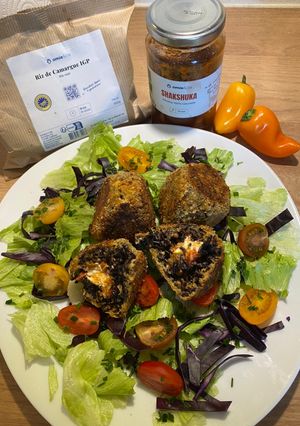 Une photo de Arancini au riz noir et shakshuka Omie, au cœur de feta et chorizo