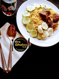 A picture of Jollof sphagetti with fried meat and cucumber and eggs and coke.