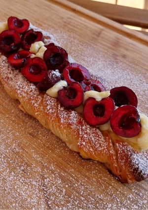 Una foto de Trenza de brioche hojaldrado con crema y cerezas