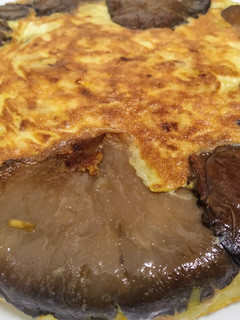 Una foto de Tortilla de patata, calabacín y puerro, abrazada por setas