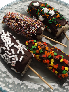 Una foto de Palitos de plátano helados cubiertos de chocolate