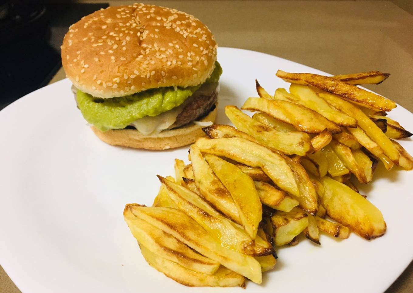 Hamburguesa con guacamole, queso, cebolla y patatas fritas al horno