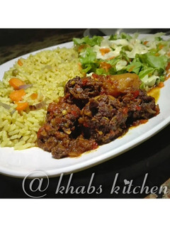 A picture of Fried rice with meat ball sauce and salad.