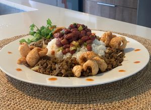 Una foto de Timbal de Arroz, Frijol & Carne Molida Con Florecitas de Chicharrón