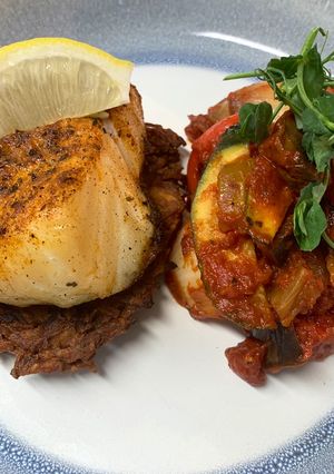 A picture of Harissa cod on a rosti served with ratatouille.