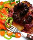 Chorizos sobre patatas y cebolla morada al horno