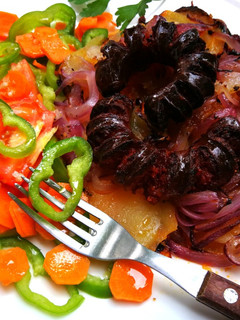 Una foto de Chorizos sobre patatas y cebolla morada al horno
