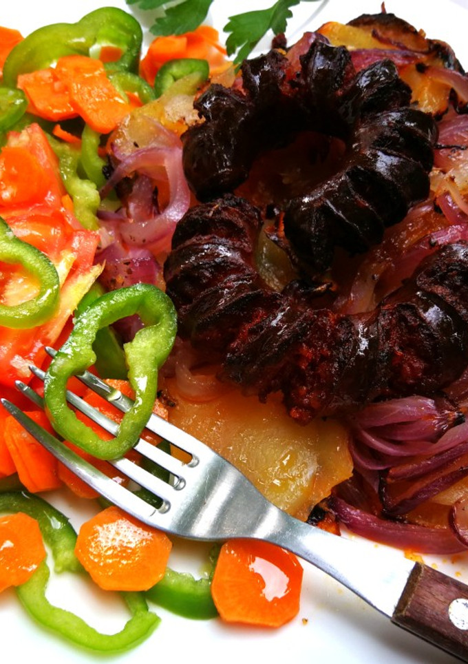 Una foto de Chorizos sobre patatas y cebolla morada al horno
