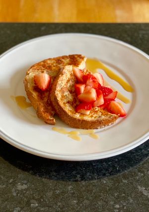 A picture of Eggy bread with strawberries and maple syrup.