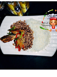 A picture of Rice and beans with veggies and fried fish.