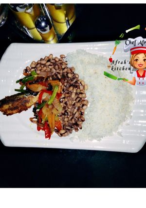 A picture of Rice and beans with veggies and fried fish.