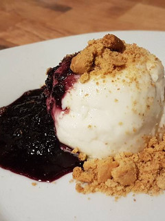 Una foto de Panna cotta de leche de cabra con mermelada de moras y galleta