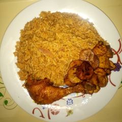 A picture of Jollof rice & ring plantain with peppered Chicken.