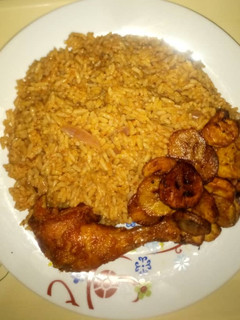 A picture of Jollof rice & ring plantain with peppered Chicken.