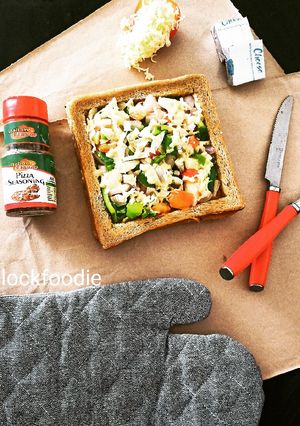 A picture of Square shaped Bread with veggies and Cheese.