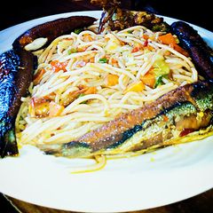 A picture of Veggie jollof spaghetti with fried fish.