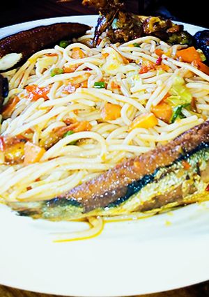 A picture of Veggie jollof spaghetti with fried fish.