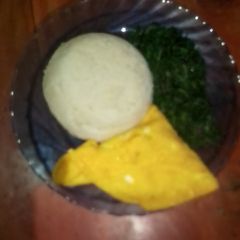 A picture of Ugali,fried eggs and green vegetables.