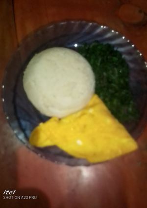 A picture of Ugali,fried eggs and green vegetables.