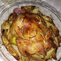 A picture of Roast chicken with potatoes,onion and garlic.