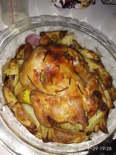 A picture of Roast chicken with potatoes,onion and garlic.