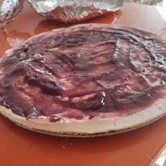 A picture of Tarta de queso con mermelada de arándanos.