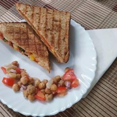A picture of Grilled sandwich filled with hummus, red sauce and vegetables.