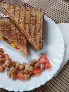 A picture of Grilled sandwich filled with hummus, red sauce and vegetables.