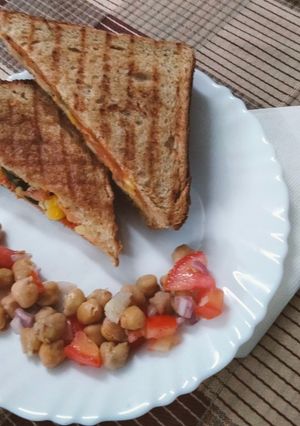 A picture of Grilled sandwich filled with hummus, red sauce and vegetables.