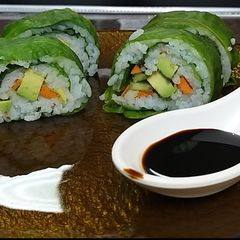 A picture of Sushi with spinach leaves.